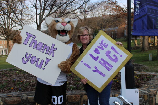 a person holding signs with a mascot