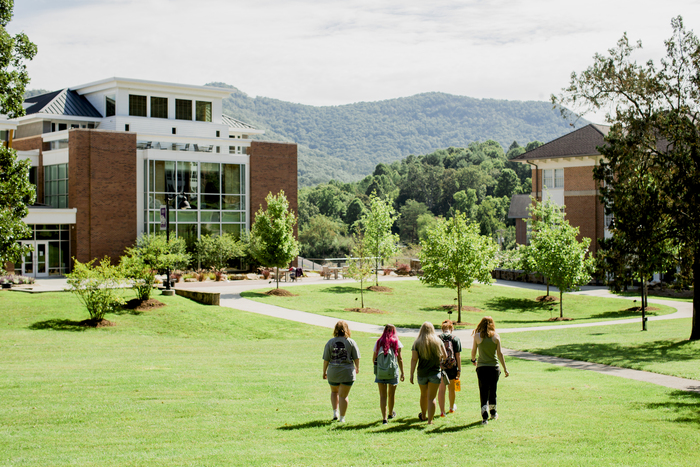 a group of people walking on a path in front of a building