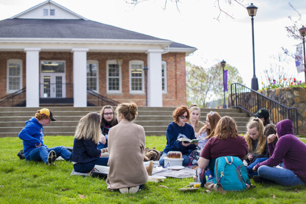 a group of people sitting on the grass in front of a building