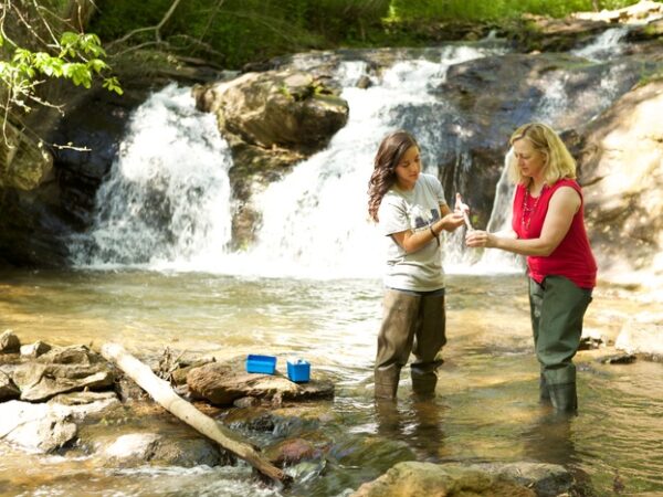 a couple of women standing next to a waterfall