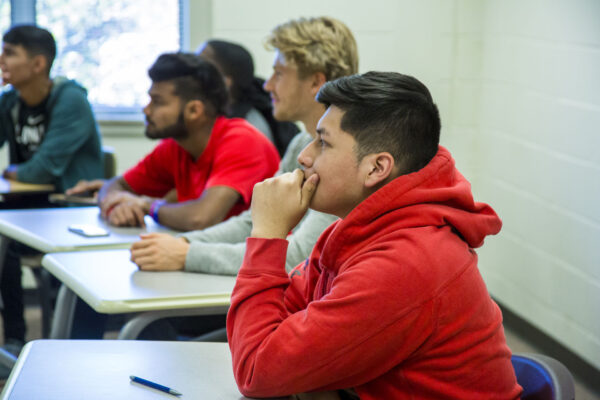 a group of people sitting at desks in a classroom