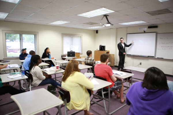 a person standing in front of a classroom with students