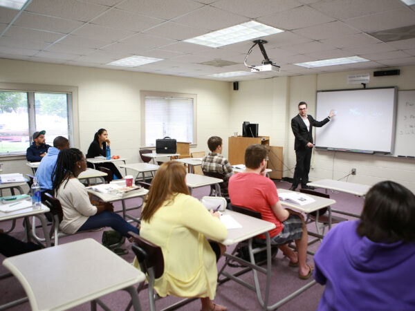 a person standing in front of a classroom with students