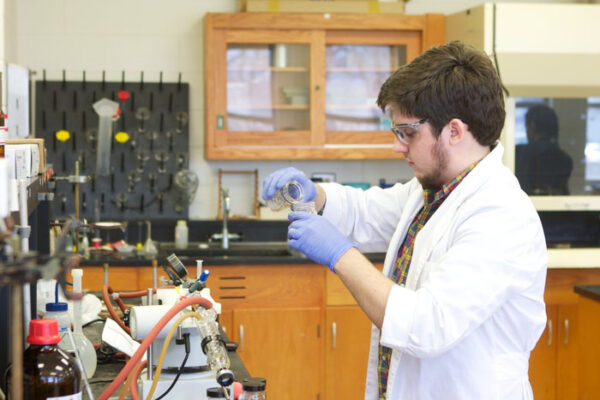 a man wearing gloves and a white coat working in a laboratory