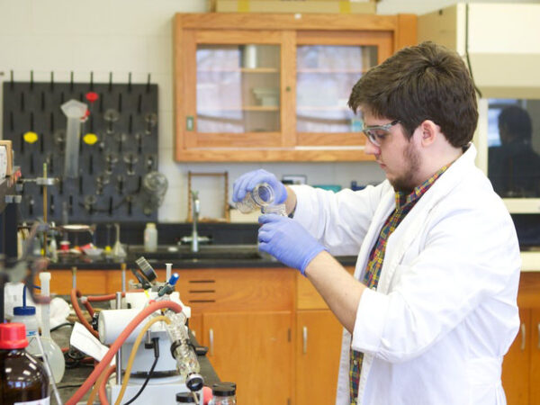 a man wearing gloves and a white coat working in a laboratory