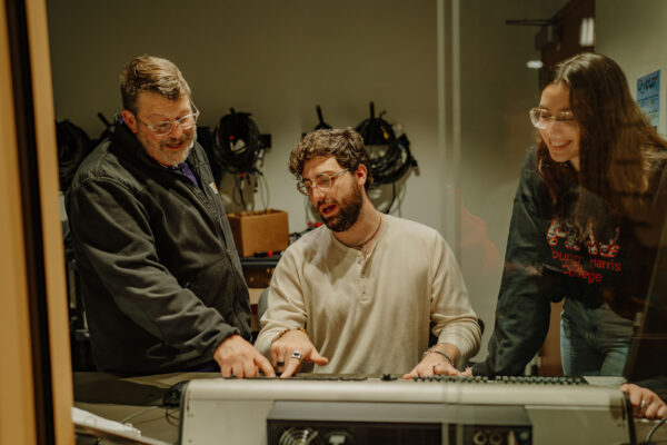 a man with a beard sitting at a sound board