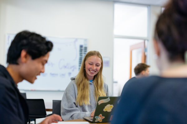 Student on laptop with other students