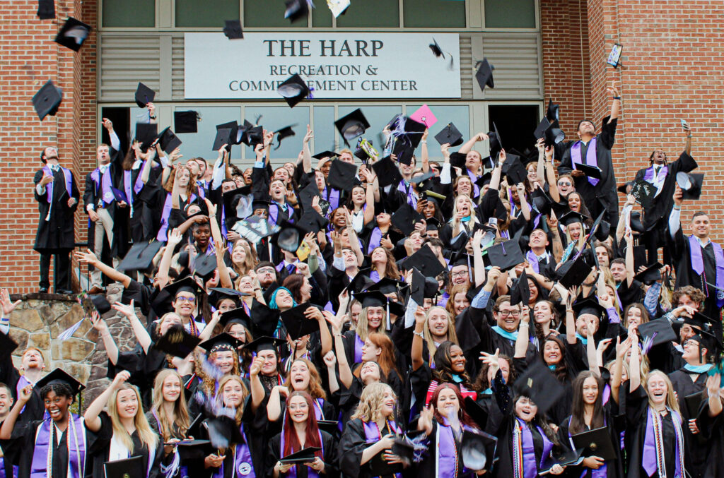 Graduates throwing caps in front of The Harp