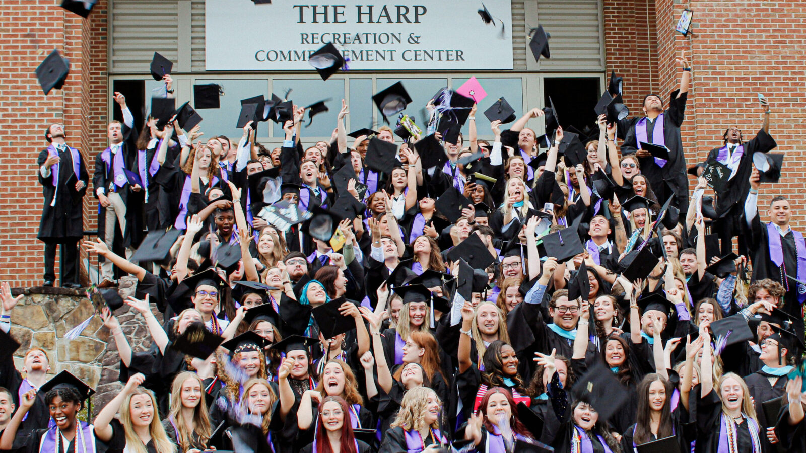 Graduates throwing caps in front of The Harp