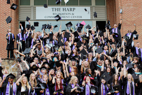 Graduates throwing caps in front of The Harp
